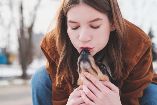 Loving and adoring pets concept: Young woman kisses her little dog