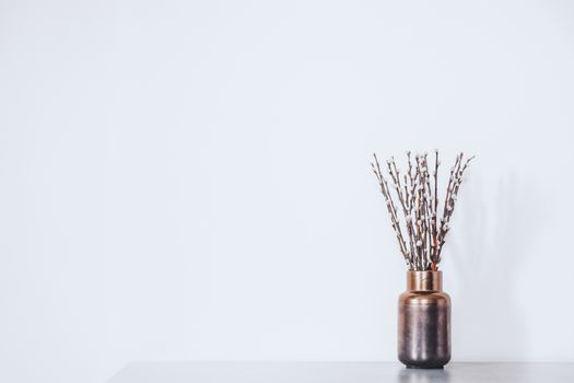 Twigs with buds in a vase against the white wall. Concept of early spring, March, nature awakening or anticipation of warm season