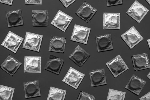 Condoms in dark monochrome background, top view. Large amount of condoms, shot from above - safe sex and contraception concept