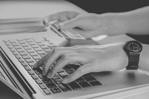 Using credit card for online payment, low key monochrome. Person filling bank account information while purchasing something in internet