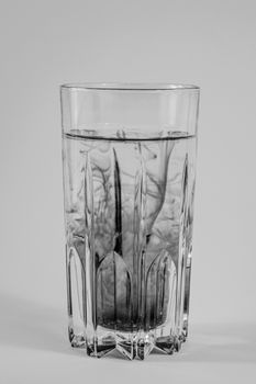 Water pollution concept. Dark substance mixing with clean water in a glass in white background