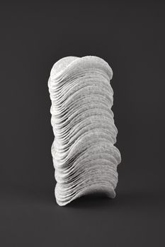 Stack of potato chips in dark background, black and white. Minimalistic image of attention grabbing fast food low-key