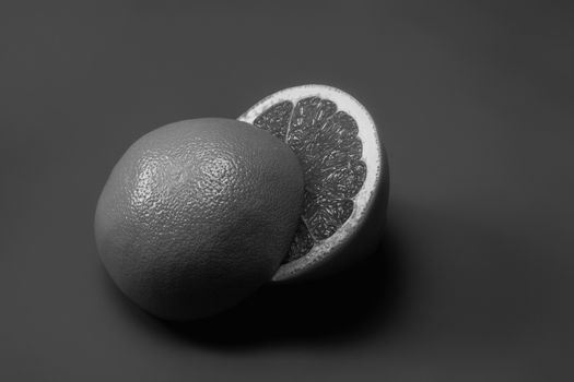 Grapefruit cut in half dark monochrome backdrop, copy space. Fruitarianism, vegetarian or vegan food: fresh and ripe citrus fruit in low key colors