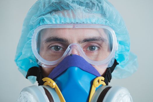 Man in protective face mask, eyeglasses and head protection, focus on eyes. Medical personell, scientist or MD in work gear, concept of covid-19, virus, epidemic and vaccine development