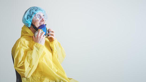 Happy medical worker puts off protective gear after a shift. Concept of covid-19 epidemic, healthcare personell and overworking in hospitals