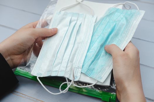 Respiratory masks in a package in human hands. Virus spread prevention means and an informational leaflet, top view