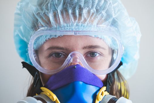 Portrait of a healthcare worker woman in protective glasses and respirator mask. Medical staff, hospital doctor or scientist developing anti virus vaccine portrait