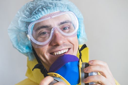 Portrait of a happy medical worker puts off protective gear after a shift. Concept of covid-19 epidemic, healthcare personell and overworking in hospitals