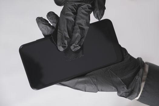 Cleaning the smartphone screen with a wipe. All black concept, personal hygiene and virus or infection spread prevention