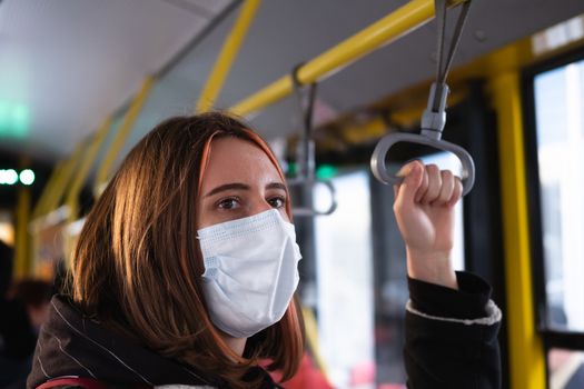 Female commuter wears a protective mask in public transport. Coronavirus, COVID-19 spread prevention concept, responsible social behaviour of a citizen