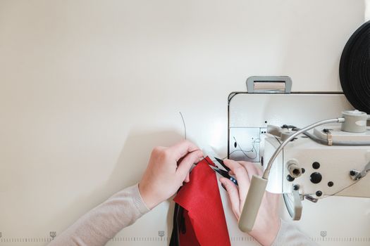 Seamstress hands at work, top view. Needlewoman at overlock sewing machine, concept of labor