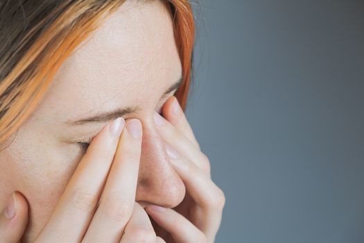 Touching face with hands, concept of bringing infection to eyes. Woman rubs eyes with fingers, tired or exhausted person