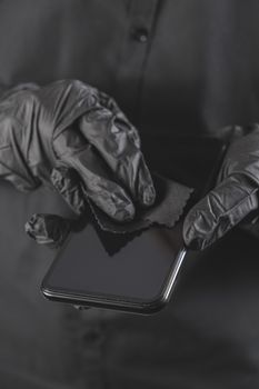 Cleaning the smartphone screen with a wipe. All black concept, personal hygiene and virus or infection spread prevention