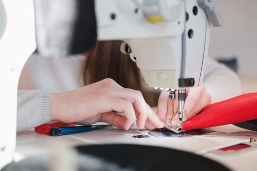 Seamstress hands doing precise work. Needlewoman at overlock sewing machine doing professional work, concept of labor