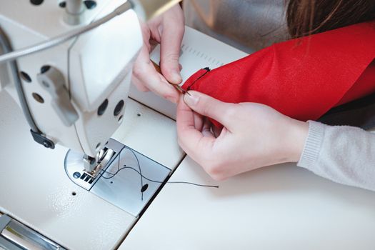 Seamstress hands at work. Needlewoman at overlock sewing machine doing professional work, concept of labor