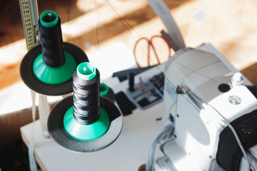 Roll of black thread next to a sewing machine. Workplace of a professional needlewoman, shot in beautiful natural light