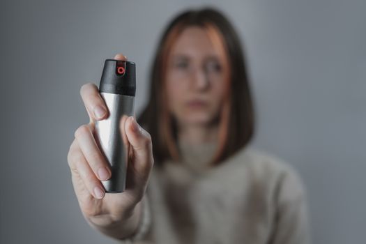 Woman with a pepper spray, low-key background. Self defence or prevention of home violence concept: using tear gas to defend yourself