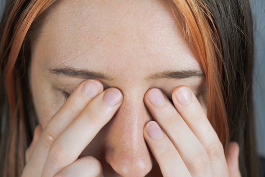 Touching eyes with fingers - concept of bringing virus or infection. Woman rubs her face with hands, personal hygiene or health care