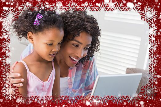 Cute daughter using laptop at desk with mother against snow