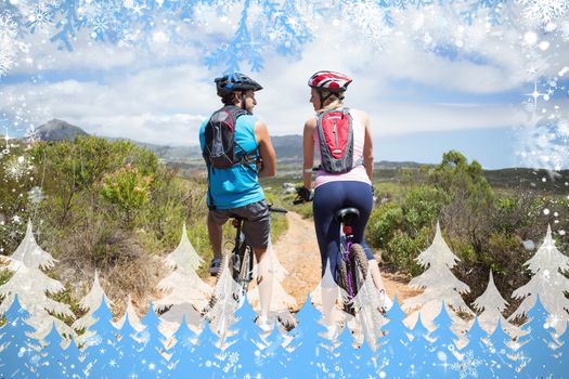 Fit couple about to cycle on mountain trail against snow