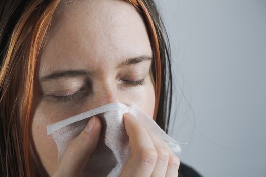 Sneezing, coughing or blowing nose in a single use paper towl. Concept of catching cold, virus or infection and not spreading it