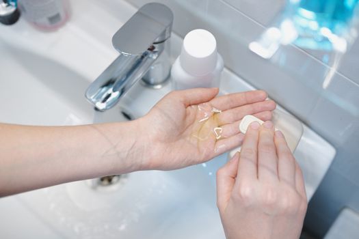 Cleaning hands with sanitizer and soap in bathroom. Concept of self protection and hygiene in epidemic conditions