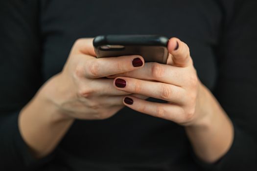 Texting on the phone, using smartphone. Female hands with a smartphone typing text and scrolling, close-up view
