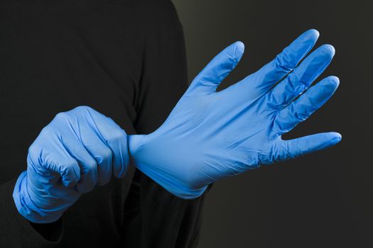 Putting on blue rubber hand gloves. Wearing protective hand gear against the infection or virus spread. Covid-19, laboratory or scientific laboratory concept