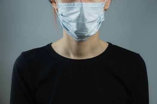 Female person in a surgical mask, minimalist and generic image. Personal protection means against virus, or germs, low-key backdrop