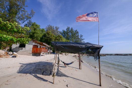 Malaysia flag waving at tent beside beach.