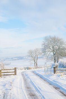 Farm track cleared of snow leading off in to the distance across snow covered fields UK