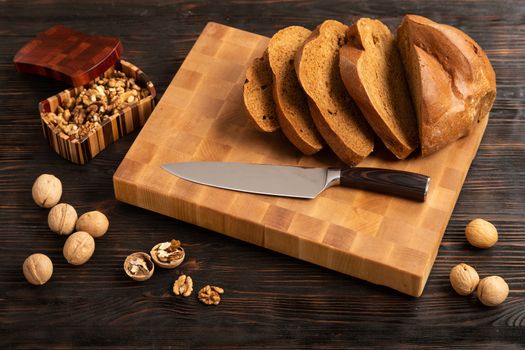 A loaf of bread sliced into slices with a knife on a wooden cutting board