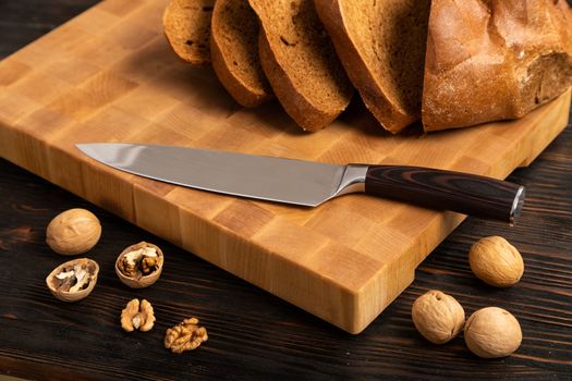 A loaf of bread sliced into slices with a knife on a wooden cutting board