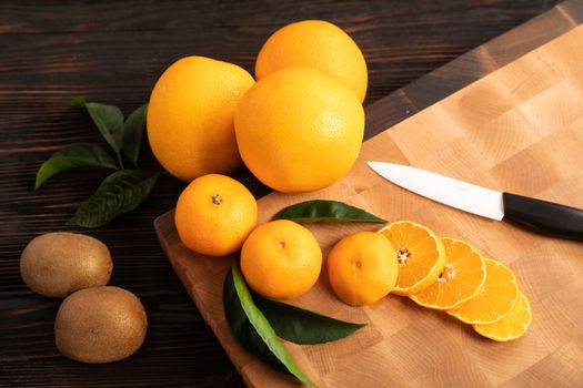 Still life with fruit. Sliced orange and other fruits on a wooden cutting board