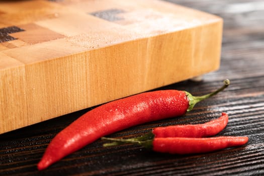 Red chili peppers next to a wooden cutting board