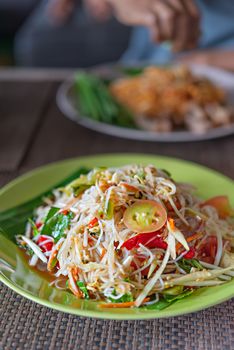 Traditional thai cuisine spicy green papaya salad with rice vermicelli