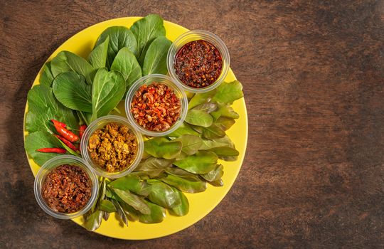 thai style chili paste served with fresh vegetables on yellow plate over wooden background