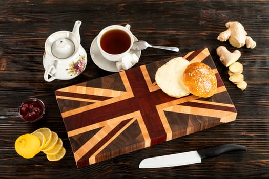 Cup of tea, sliced lemon and a bun on a wooden cutting board