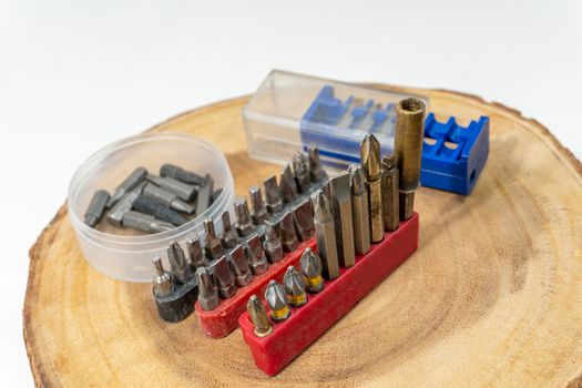 Screwdriver bits and tips lie on a round cut of wood in a carpentry workshop