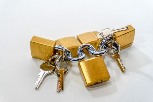 Small bronze locks with steel keys lie on a white background