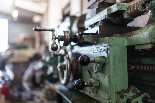 The old lathe machine is painted green. A small workshop for metal processing. Screw turning machine produced in 1963