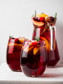 Winter sangria on tabletop. Glasses of sangria with fruit slice, cranberry and rosemary. Vertical. Copy space for text or design.