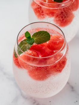 Watermelon ice with sparkling water or soda in glass tumbler. Summer party idea and recipe, add color and flavor for soda or other drink. Vertical