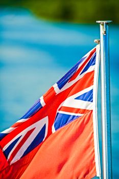 red with with Union Jack blowing in the wind on the back of a boat UK