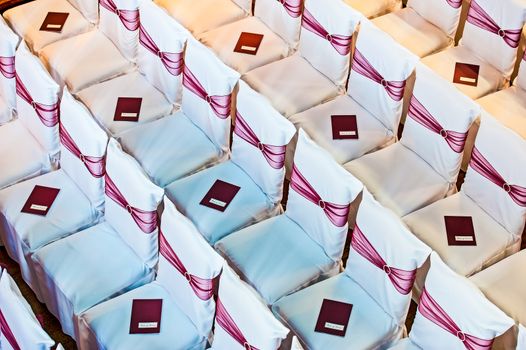 white covered wedding chair with maroon sashes and silver brooche