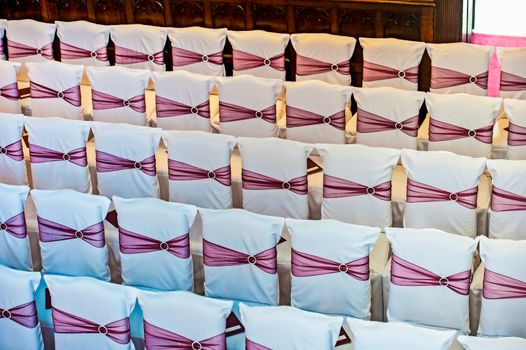 white covered wedding chair with maroon sashes and silver brooche