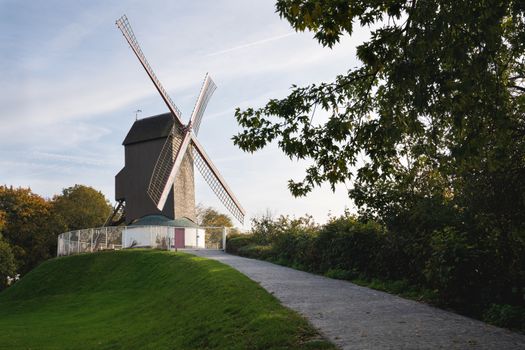 Historic windmill close to the canals of Bruges with autumnal colored trees, Belgium