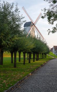 Historic windmill close to the canals of Bruges with autumnal colored trees, Belgium