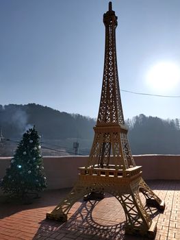 A second Eiffel Tower outside of Paris with Christmas decorations and sun in the background.
