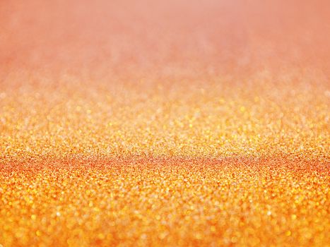 Golden abstract background with shiny glitter. Orange festive sparkling macro texture. Holiday backdrop with copy space.